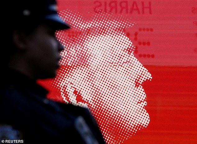 A New York police officer stands in front of an image of Republican presidential candidate and former US President Donald Trump outside Madison Square Garden on the day of Trump's rally.