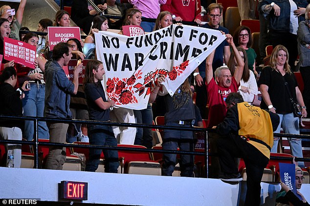 A separate group of protesters unfurl a banner in another part of the stadium in Madison before being removed.