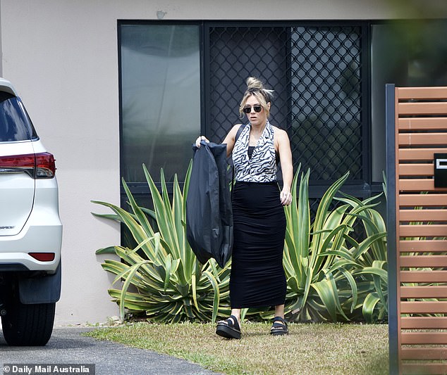 The mother of four leaves the house Wednesday morning with a dry cleaning bag.