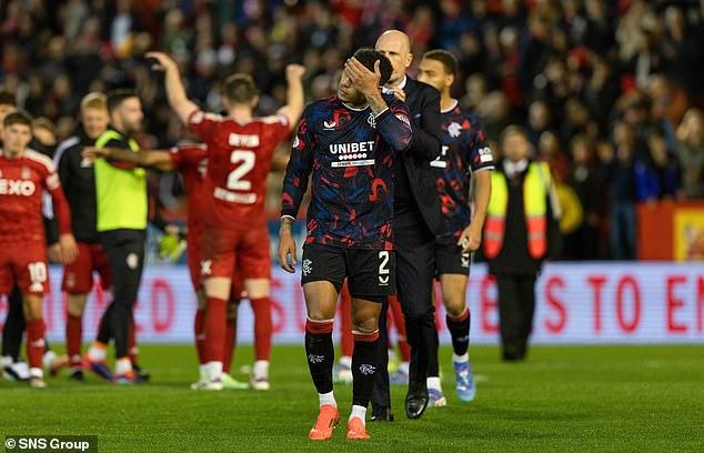 Rangers captain James Tavernier leaves the field as the victorious Dons stars celebrate