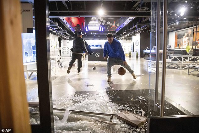 Looters can be seen playing basketball inside a vandalized Nike store in downtown Los Angeles.