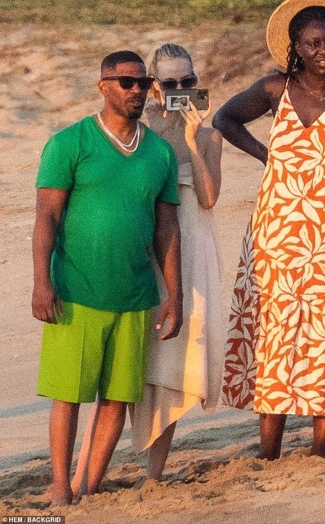 The group was seen strolling along the beach, with the comedian recognizable in a green V-neck t-shirt and lighter green shorts.