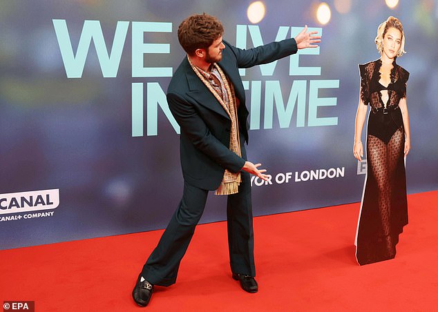 Andrew looked dapper in a blue suit with flared trousers, a pink and blue striped shirt and a long, thin printed scarf as he posed alongside Florence's stand-in.