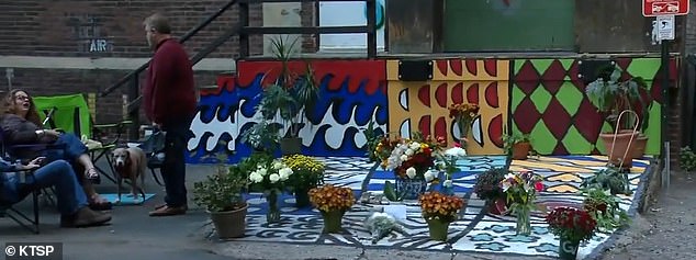 Pictured: The mural Kwok had been working on when he was shot. Friends and loved ones have since placed flowers.