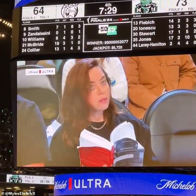 The Community star, 40, was sitting courtside to watch the game and pretended to read a book as the action unfolded just inches from her.