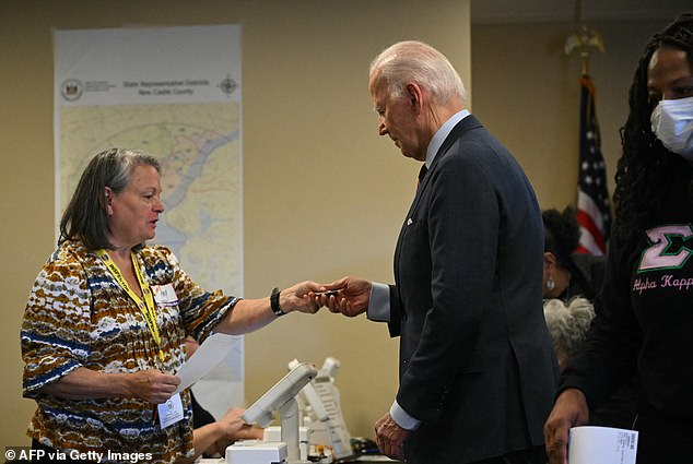 Biden hands over his driver's license as proof of identification while casting his early vote in New Castle, Delaware.