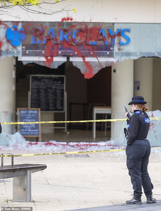 A police officer is at the scene in Bristol after activists attacked a Barclays branch on June 10.