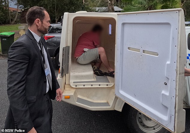 The man is seen sitting in the back of a police van after being arrested on Wednesday.