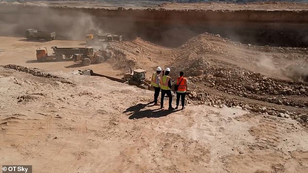 Construction workers stand at the edge of a large trench being dug for The Line's megacity.