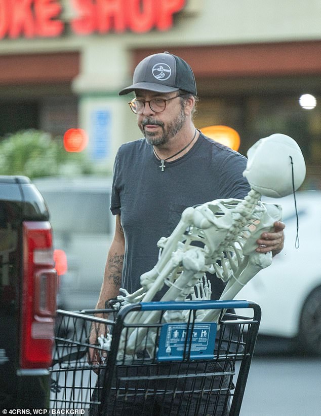 The rocker prepared for the upcoming holiday, pushing a cart full of decorations, including two life-size skeletons.