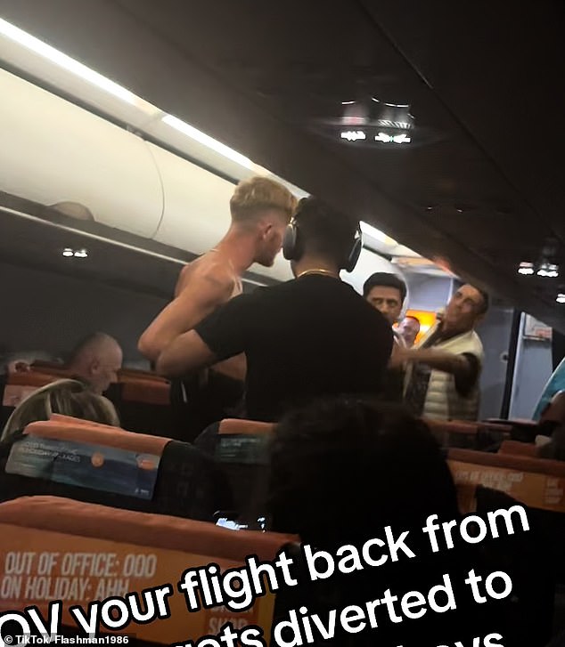 Another passenger in a black T-shirt and headphones appears to be trying to reduce tension