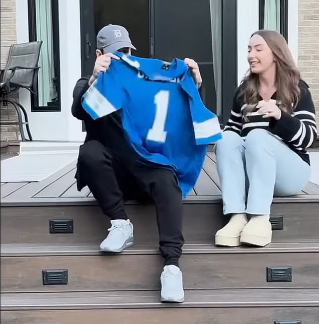 While sitting outside on a terrace, her daughter handed her a blue shirt which she held up to show that 