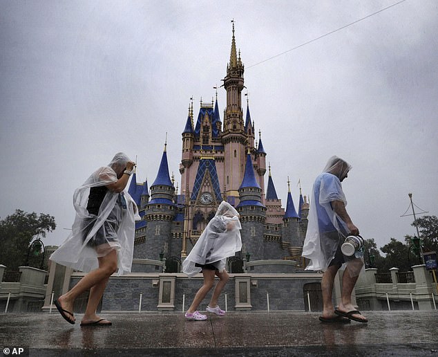 Disney World visitors jog through the theme park during rain related to Hurricane Milton