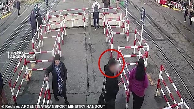 Facundo Rodríguez (circled) was almost hit by a train in Buenos Aires, Argentina, because he was distracted by his cell phone while crossing the street Monday morning.