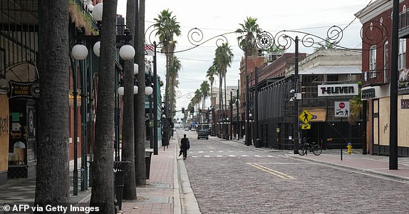 A resident walks on a deserted street in the Ybor City section of Tampa ahead of the expected landfall of Hurricane Milton mid-week on October 8, 2024 in Florida. Hurricane Milton exploded with force on October 7 to become a potentially catastrophic Category 5 storm headed for Florida, threatening the US state with a second ferocious hurricane in as many weeks. (Photo by Bryan R. SMITH/AFP) (Photo by BRYAN R. SMITH/AFP via Getty Images)