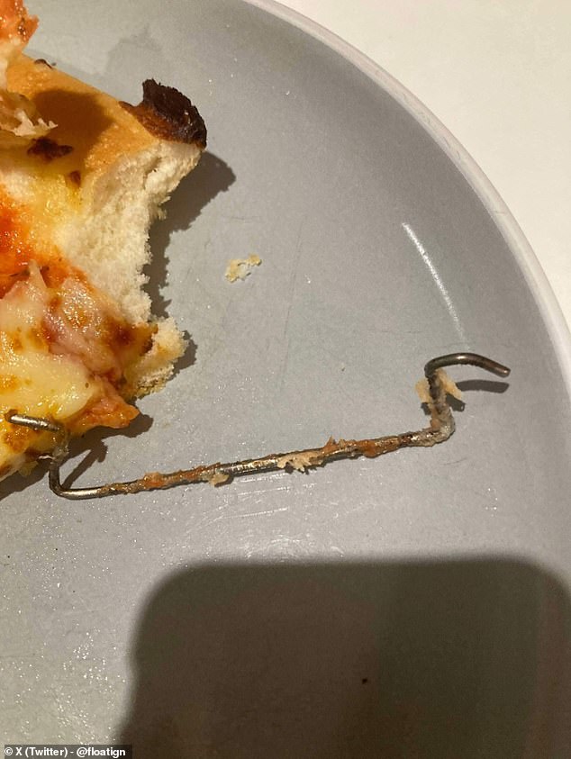 The sharp object, which has hooks on both ends, covers almost the entire edge of a pizza slice.