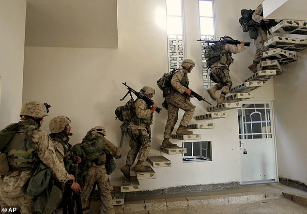 US Marines from the 1st Division enter a house to take up positions in western Fallujah, Iraq, in 2004.