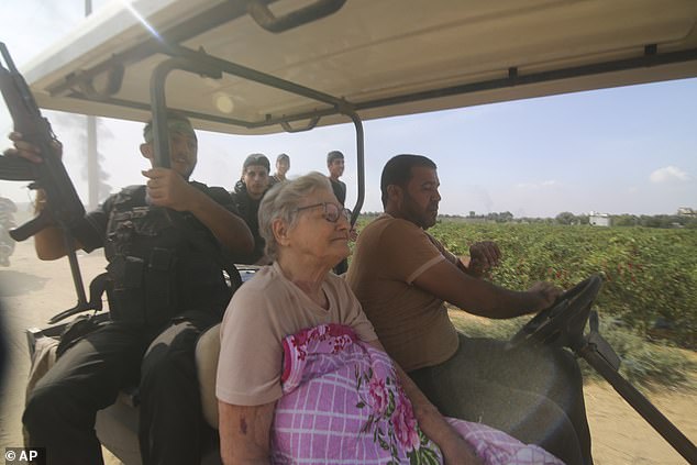 Palestinians transport a captured Israeli civilian, center, from the Kfar Azza kibbutz to the Gaza Strip on Saturday, October 7, 2023.