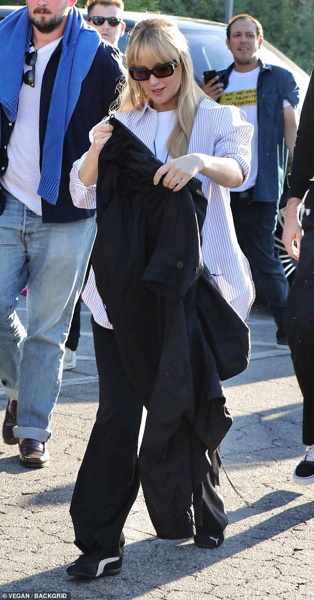 For the high-profile sporting event, the actress wore loose-fitting black pants, a white T-shirt, and a white button-down shirt with blue stripes.