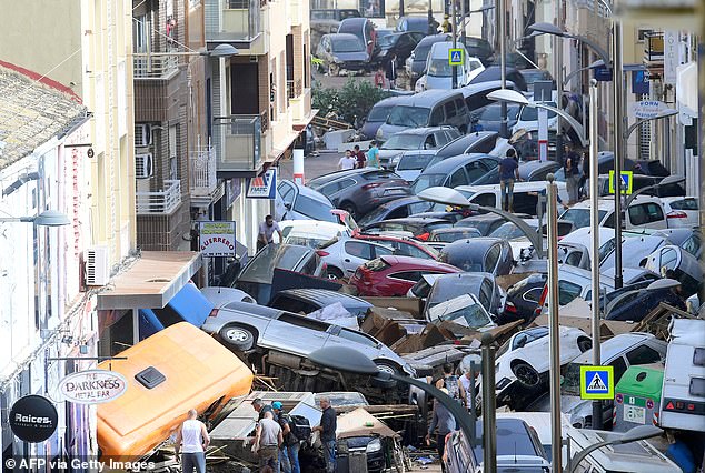 Pedestrians stand next to cars piled up after deadly flooding in Sedavi, south of Valencia, eastern Spain, on October 30, 2024.