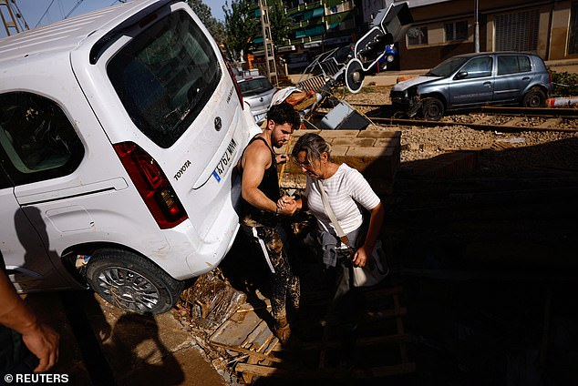 People stand next to stranded cars after flooding in Valencia, Spain, on October 31, 2024.