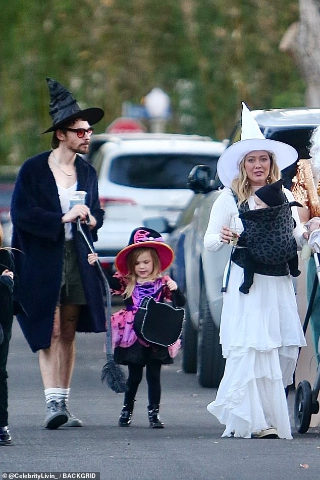 On Thursday, Hilary celebrated Halloween with her family as a white witch in a pointy hat. Matthew contrasted her in a black ensemble with his own tall hat.