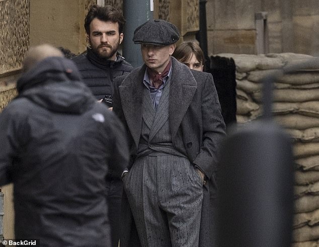 The Saltburn star looked every inch Peaky Blinder in a flat cap, gray suit and coat while on set.