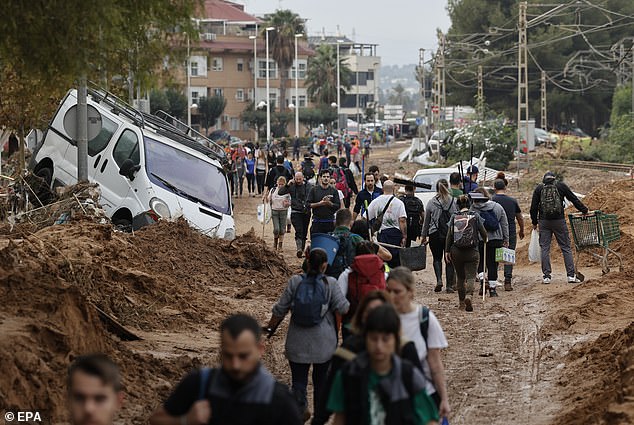 People walk through an affected area of ​​Paiporta, Vallencia. The streets have been filled with sediment from floods and cars destroyed by the force of the water