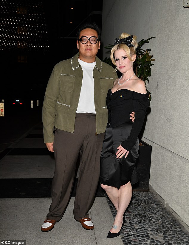 Kelly cut a glamorous figure for the night as she donned a strapless black top with a sweetheart neckline (pictured with friend Daniel Nguyen).