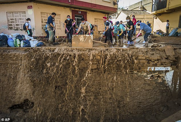 People in PPE try to sweep mud as they desperately clean the streets