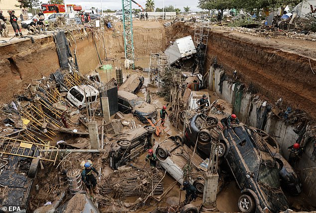 Cars piled up in a ditch at a construction site after being swept off the road by heavy flooding