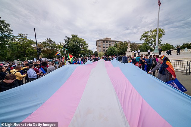 A giant trans flag is displayed outside the Supreme Court during the Court's previous hearing on a case dealing with LGBTQ rights. The Biden administration asked the court to take up the new case, after a lower court upheld a ban on surgeries and treatments in Tennessee.