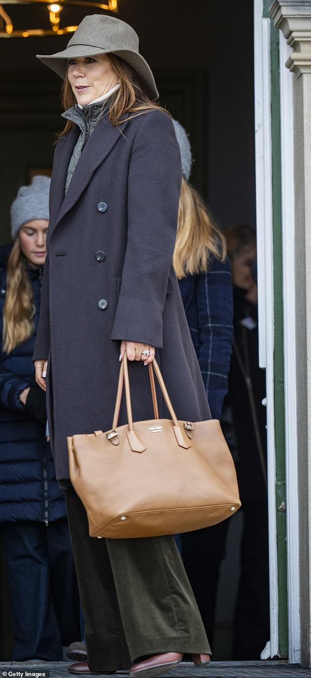 Mary accessorized her look with a wide-brimmed gray hat and a tan Prada shopper bag.