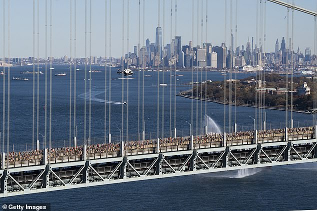 Runners cross the Verrazzano-Narrows Bridge with the Manhattan skyline in the background