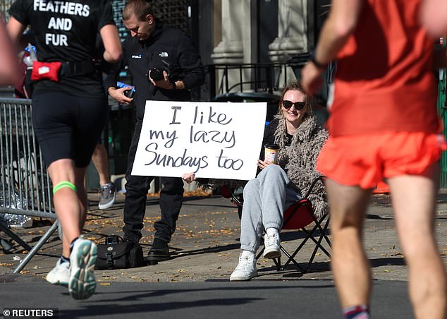 A spectator holds a sign that says 