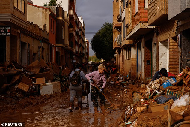 A woman cleans thick mud, after flooding caused by heavy rain, in Sedavi, near Valencia, Spain, on November 3, 2024