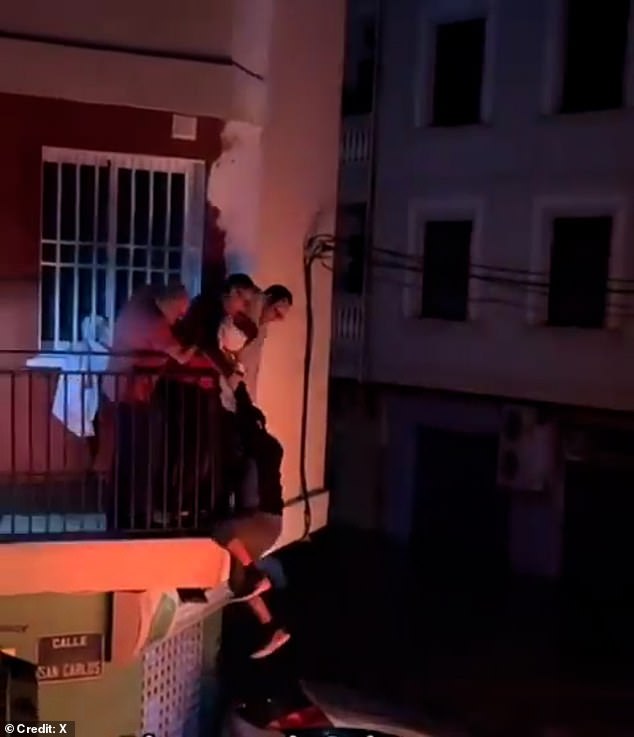 Three good Samaritans come to his rescue by passing a blanket across the metal railings from the first floor to the man below before carrying him to safety.