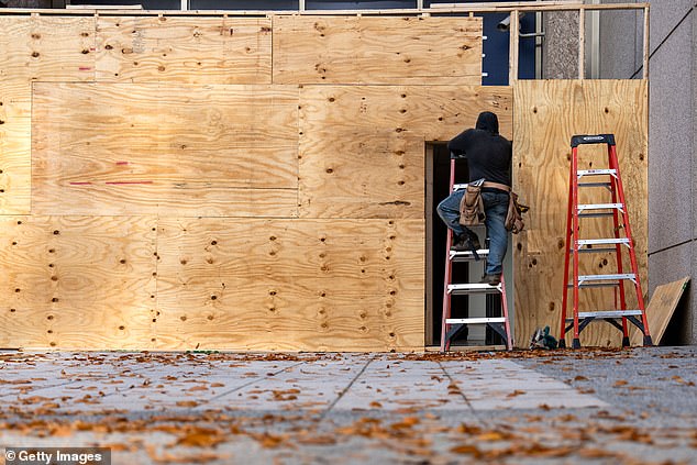 Workers are seen boarding up storefronts and buildings at ground level along Pennsylvania Avenue near the White House.