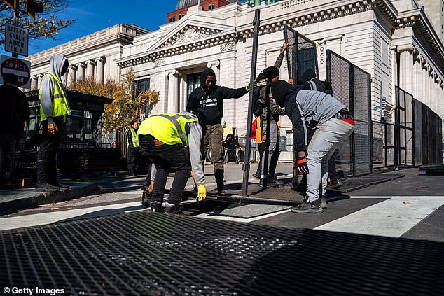 Workers erect anti-climb fencing around the White House and the Treasury Department on Sunday.