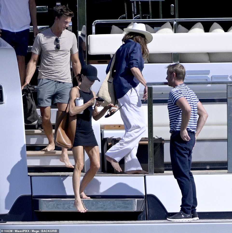 Victoria, 50, turned heads in a thigh-high black summer dress as she walked barefoot on the terrace.