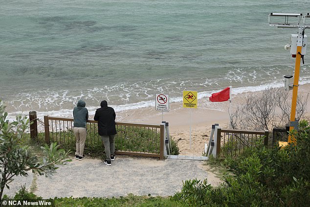 The father desperately tried to reach his son, who was swept away by the strong tide, but was unable to do so (in the photo, men believed to be relatives or friends guard the stretch of water where the boy was swept into the sea)