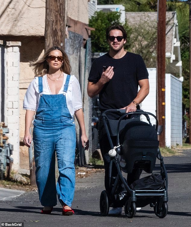 Her husband walked beside her as he proudly pushed a sleek black stroller with their little one.