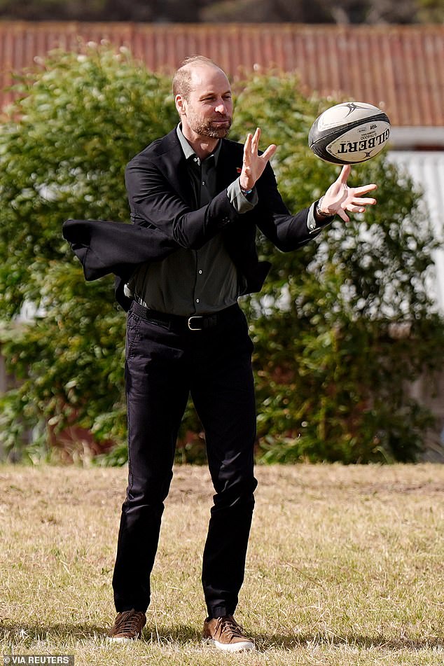 William wears the bracelet as he catches a ball at a rugby session in Cape Town yesterday.