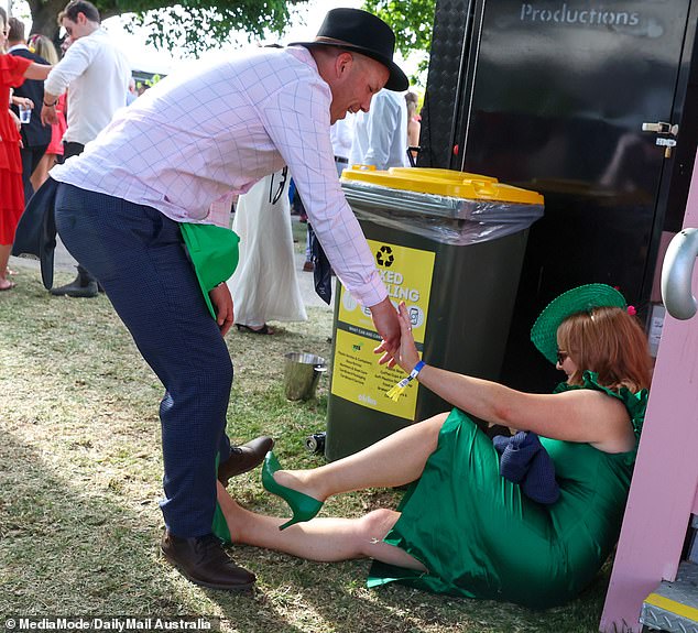 An obedient friend was pictured helping his friend up after she fell to the ground next to the bins.