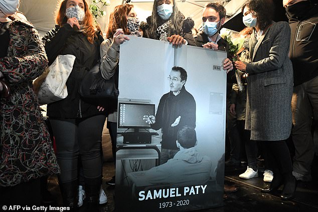 Family and colleagues hold a photograph of Samuel Paty