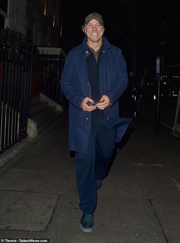 John Bishop was apparently in good spirits as he smiled upon arriving, wearing a blue coat over a sweater and shirt with a baseball cap to finish off the look.