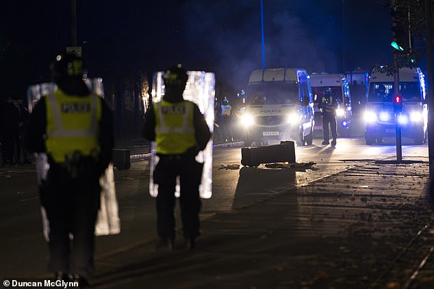 Riot police in Niddrie, Edinburgh, Scotland, as fireworks, stones and glass bottles are thrown at them after rioting began in the Scottish capital area.