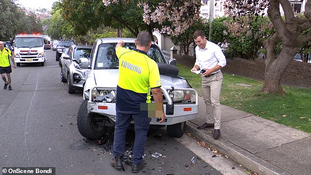 A witness and the tow truck driver appeared to be assessing the damage at the accident site.