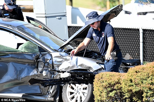 Two police officers were also injured when the allegedly stolen car collided with their police vehicle (pictured, a police officer at the scene of the accident on Thursday).