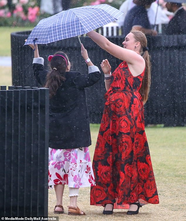 Racegoers huddled under umbrellas once rain hit Flemington on Thursday.